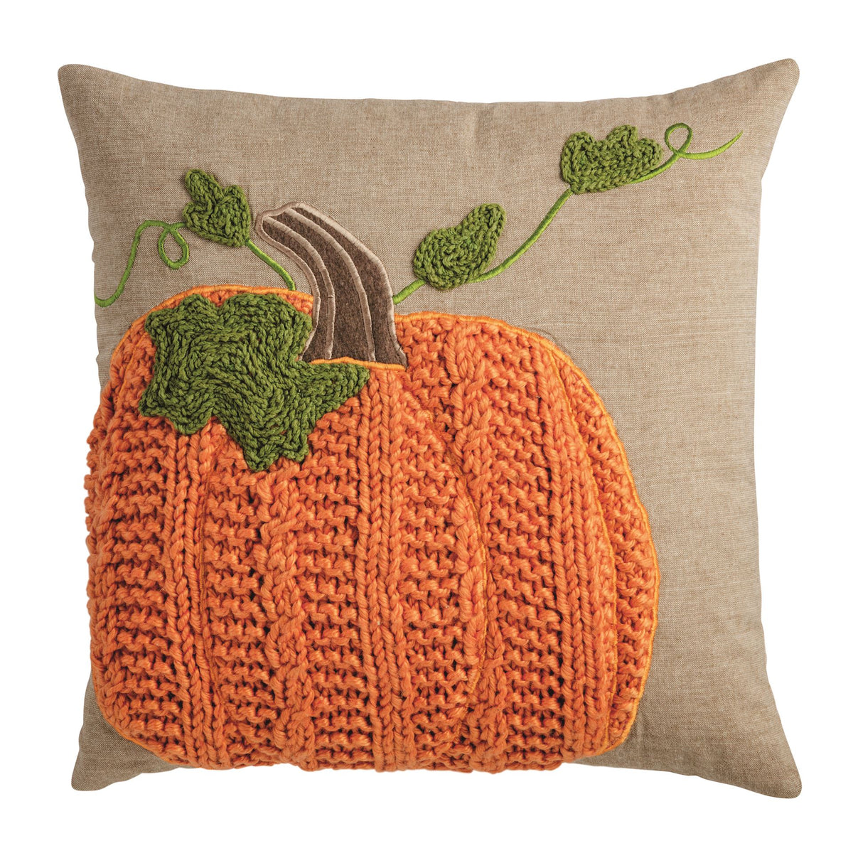 A square beige linen throw pillow featuring a large, textured orange knitted pumpkin applique with green leaves and a brown stem, set against a plain white background.
